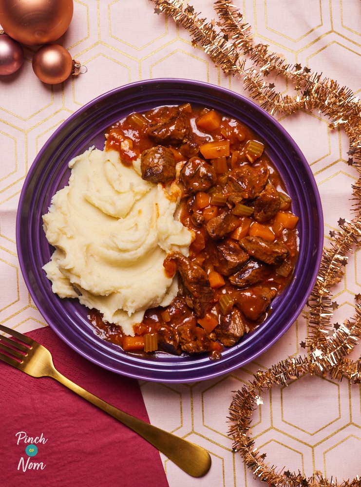 Pinch of Nom's Mulled Wine Beef Stew is served in a large, shallow blue bowl, alongside a mountain of creamy mashed potatoes.