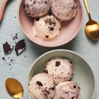 Two bowls of Pinch of Nom's slimming-friendly Ninja Creami Cookies and Cream Ice Cream are served with three scoops in each, with gold-plated spoons ready to dig in.