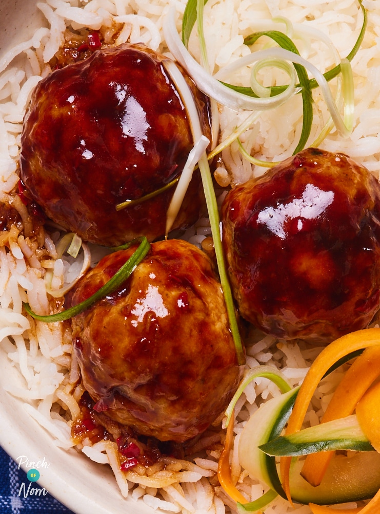 A close up shows Pinch of Nom's Sweet Chilli Meatballs served on a bed of rice. The meatballs are coated in a glossy, sticky sauce.