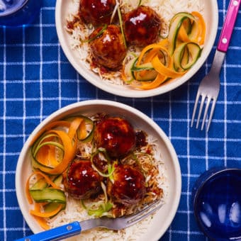 Two portions of Pinch of Nom's Sweet Chilli Meatballs are served in white bowls, with rice and ribbons of carrot and courgette.