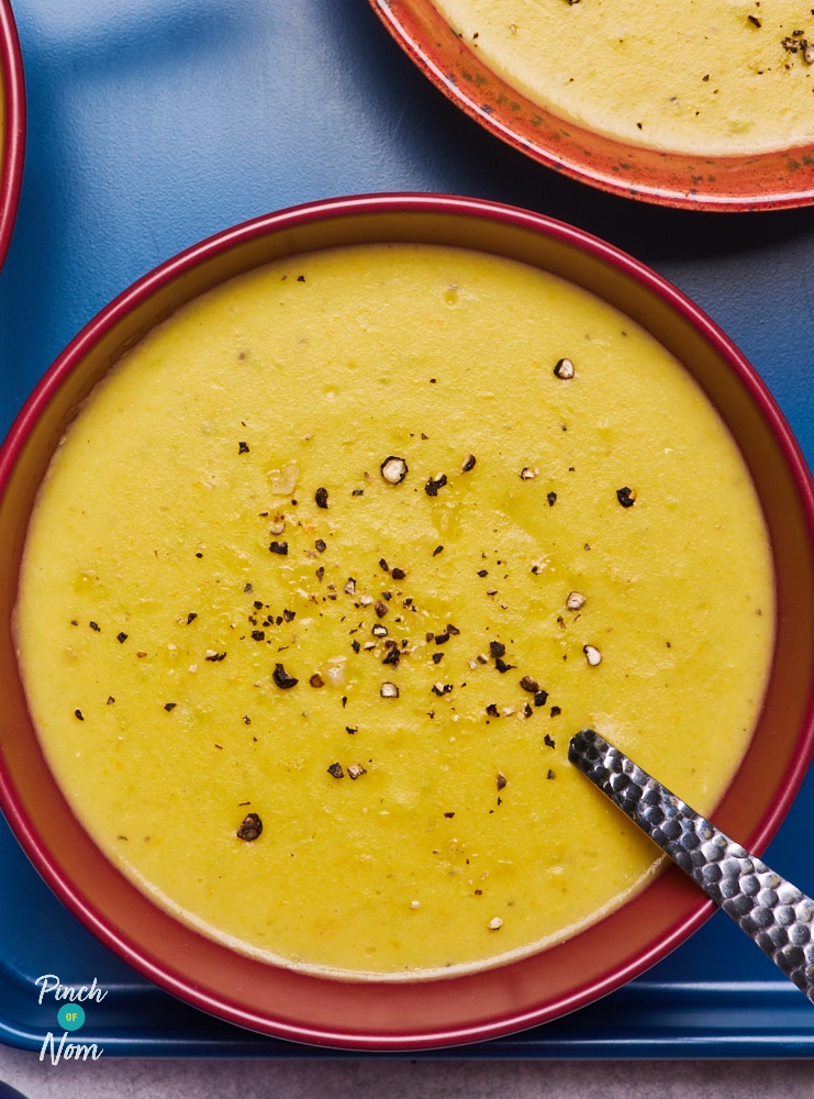 A bowl is filled with Pinch of Nom's slimming-friendly Creamy Vegetable Soup, with a spoon waiting to tuck in. There is a scattering of freshly ground black pepper on top, to liven up the flavours.