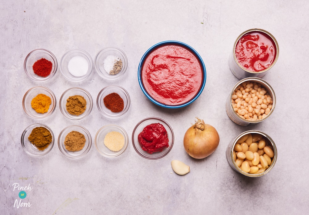 The ingredients for Pinch of Nom's Tikka Beans are laid out on a kitchen counter, ready to begin cooking.