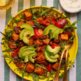 Roasted sweet potato salad on a plate, topped with avocado.